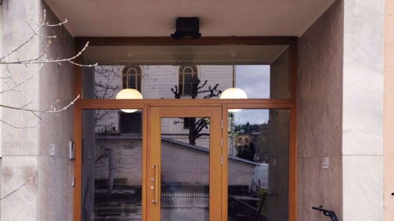 Säkerhetsdörr i massiv ek med över- och sidoljus i personskyddat isolerpaket på Artillerigatan i Stockholm.
